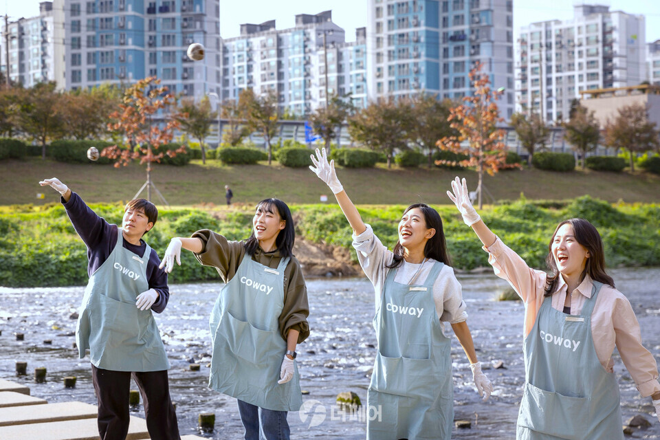 코웨이 임직원 봉사자가 안양천 다리에서 EM흙공을 던지고 있다. / 사진제공=코웨이