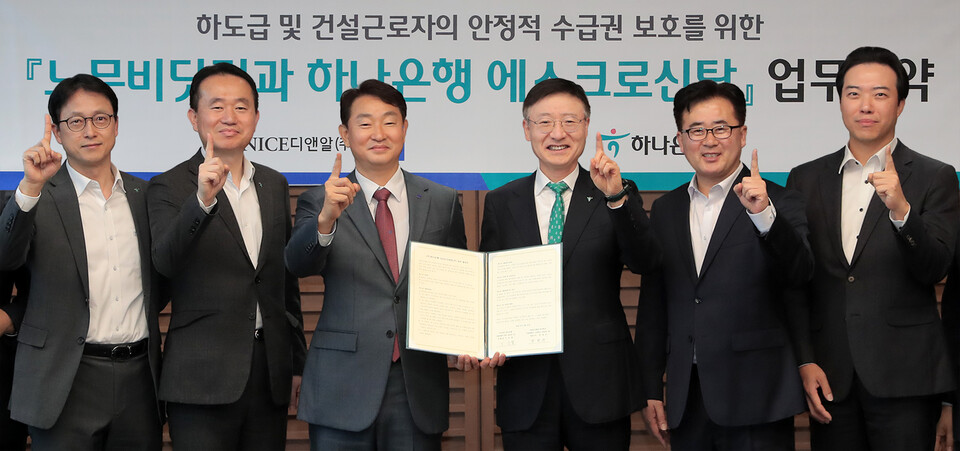 사진제공=하나은행 / 하나은행은 지난 21일 하나은행 을지로 본점에서 나이스디앤알과 건설근로자의 임금체불 피해 방지 및 영세 건설사업자의 공사대금 결제환경 개선을 위한 업무협약을 체결했다. 이승열 하나은행장(사진 왼쪽에서 네번째)과 박정우 나이스디앤알 대표이사(사진 왼쪽에서 세 번째)가 협약식에 참석한 양사 관계자들과 ‘하나’를 의미하는 포즈를 취하며 기념촬영을 하고 있다.