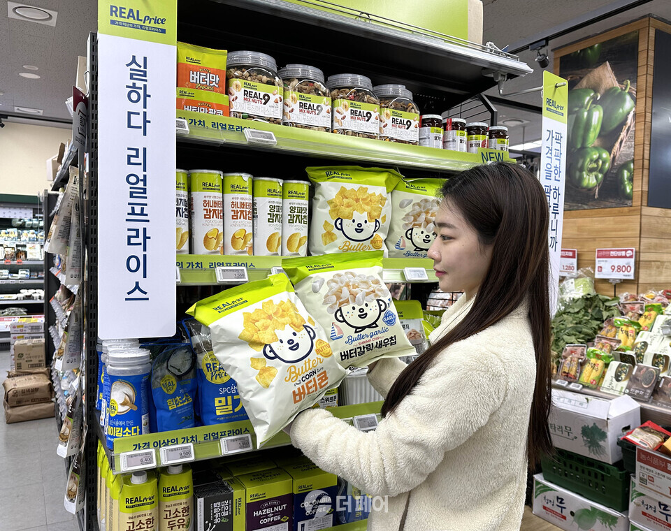 GS더프레시에서 모델이 리얼프라이스 스낵 제품을 들고 포즈를 취하고 있다. / 사진제공=GS더프레시