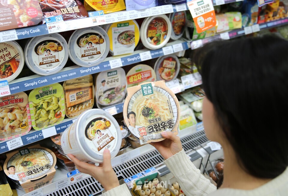 모델이 GS25에서 편스토랑 장민호의 꾸덕명란 크림우동과 혜자로운 바삭킹튀김우동 상품을 보고 있다. / 사진제공=GS25