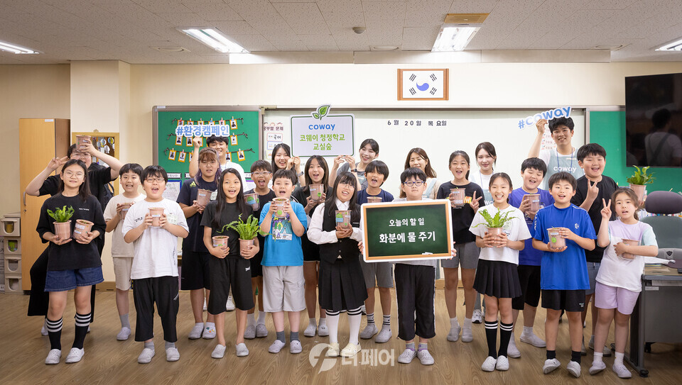 코웨이 임직원 봉사자들과 초등학생들이 청정학교 교실숲 제6호 조성 기념 단체 사진을 찍고 있다. / 사진제공=코웨이