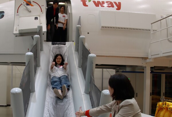 지난 8일 오후 티웨이항공 훈련센터에서 객실 승무원 체험 활동에 참여한 속초양양지역 중학생들이 B737 항공기 슬라이드 훈련을 체험하고 있다 / 사진=티웨이항공