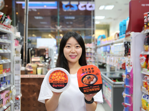 GS25에서 모델이 제로밥상 옛날떡볶이와 최강제육덮밥을 들고 포즈를 취하고 있다. 사진= GS25