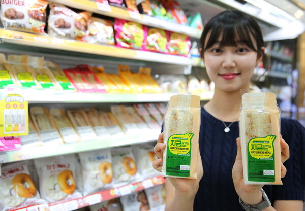 모델이 GS25가 국내산 마늘 소비 촉진 취지로 출시한 갈릭치킨포테이토샌드위치를 들고 포즈를 취하고 있다. 사진=  GS25