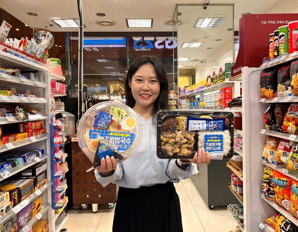 고객이 GS25에서 팔도 삼겹구이한판 도시락, 팔도 우삼겹주먹밥, 팔도 비빔국수&왕교자를 들고 포즈를 취하고 있다. 사진= GS25
