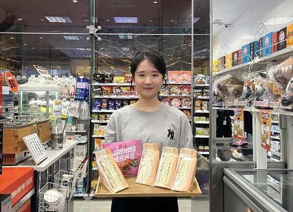 GS25에서 모델이 나트륨을 낮춘 아삭오이크림치즈샌드위치와 스리라차마요비프버거를 선보이고 있다. 사진= GS리테일