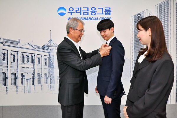 우리금융그룹 임종룡 회장이 그룹의 새 가족이 된 동양생명·ABL생명 직원에게 디지털 선도의 의미가 담긴 새로운 그룹 보조휘장을 달아주고 있다. 사진=우리금융그룹